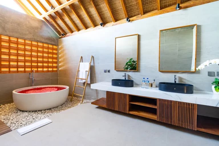 Spacious bathroom in bedroom three at Jiwoku Villas Canggu Bali with flower-filled bathtub, double vanity, and natural lighting